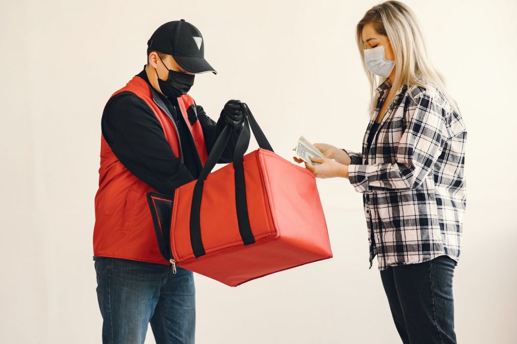 young female customer receiving meal order during coronavirus pandemic